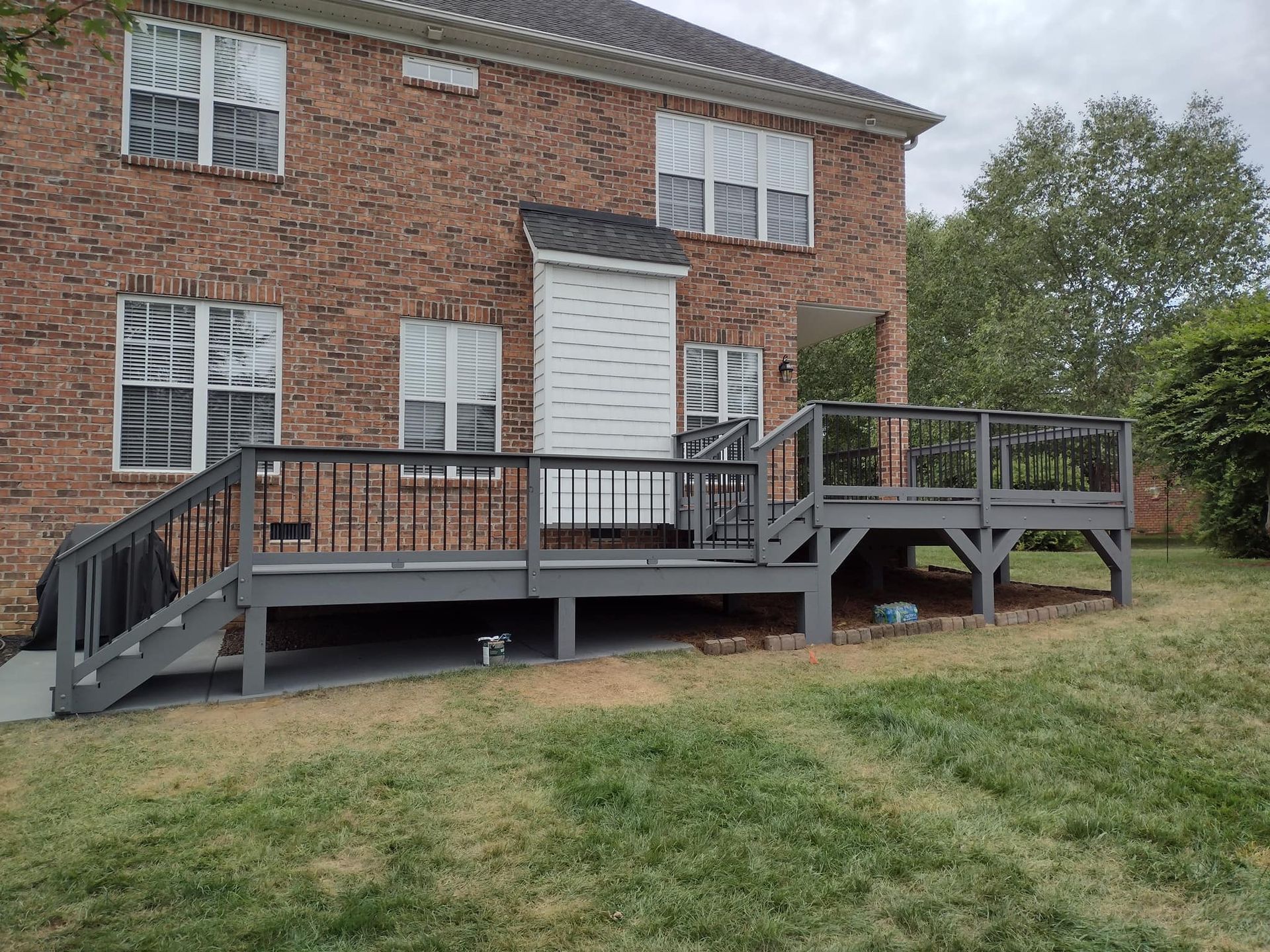 A large brick house with a large deck in front of it.