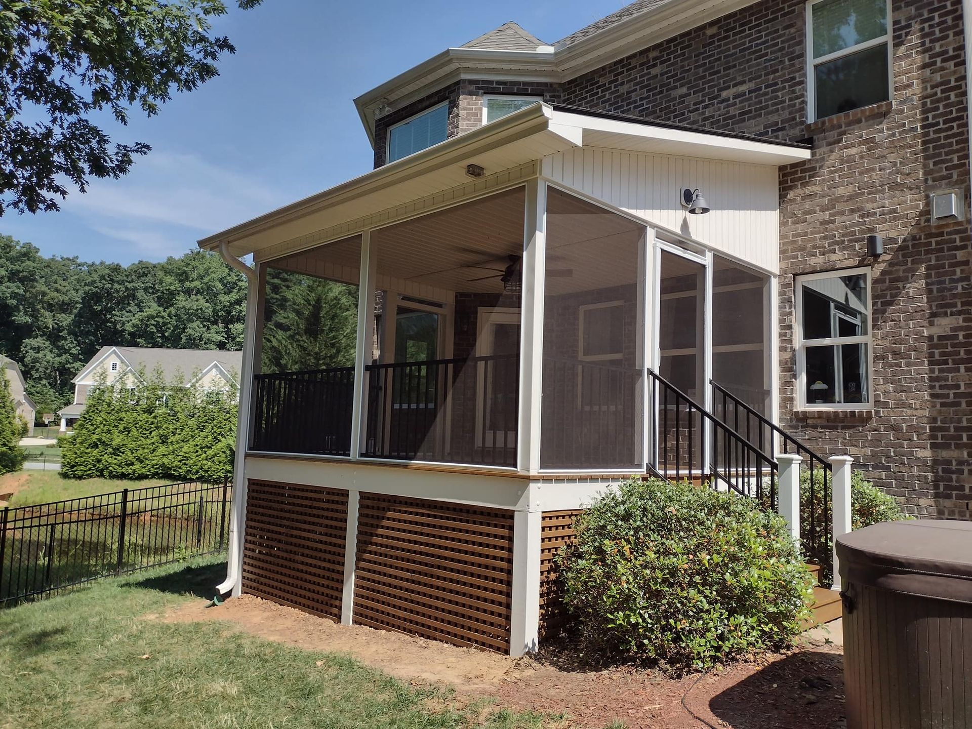 A screened in porch on the side of a brick house.