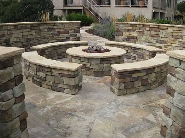 A fire pit is surrounded by stone walls and benches.