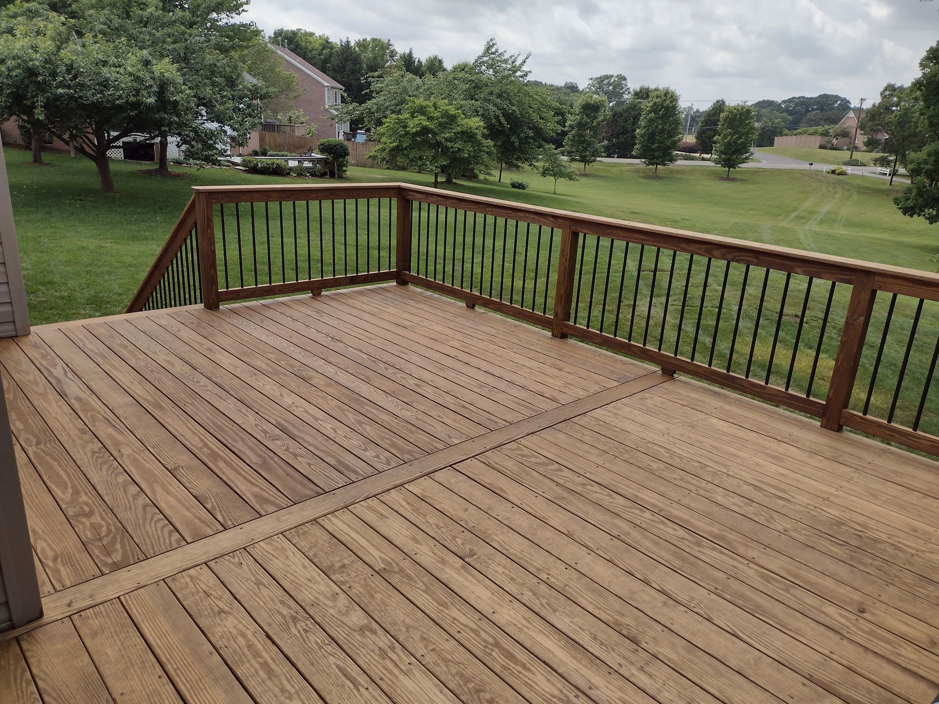 A large wooden deck with stairs leading up to it is surrounded by trees.