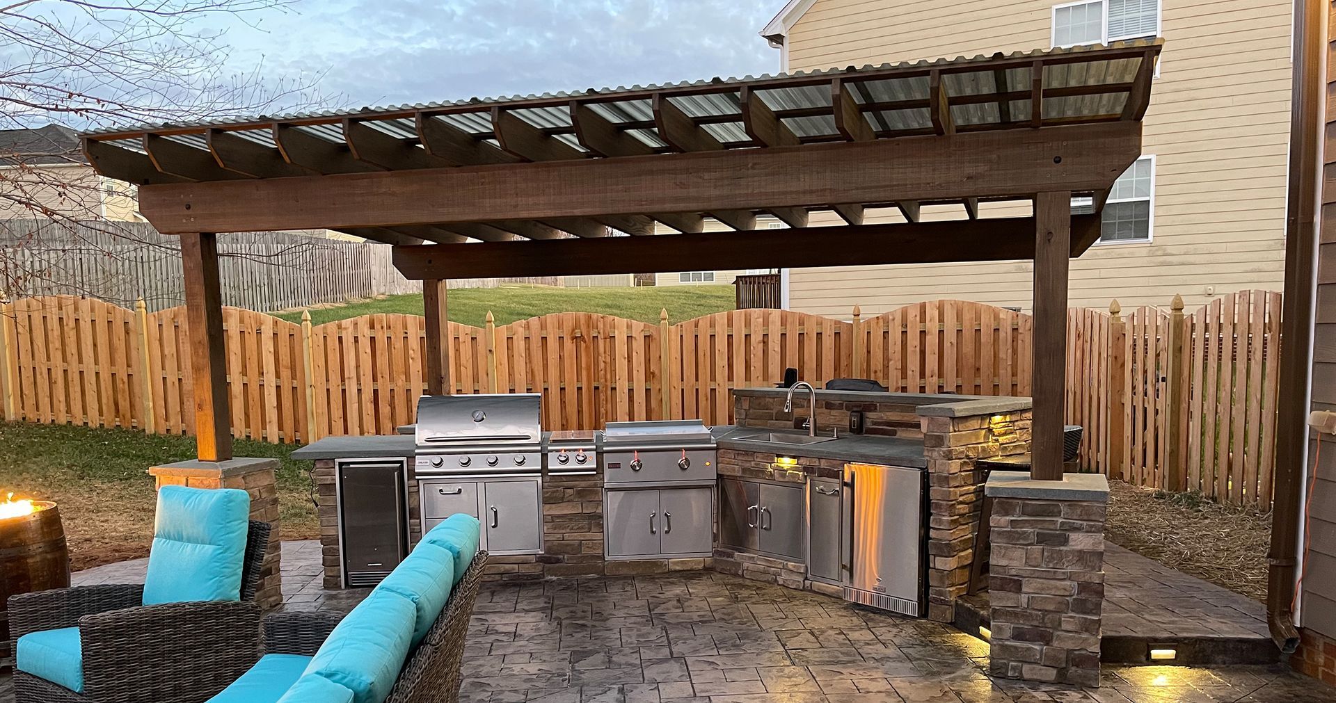 A large outdoor kitchen with a pergola and a grill.
