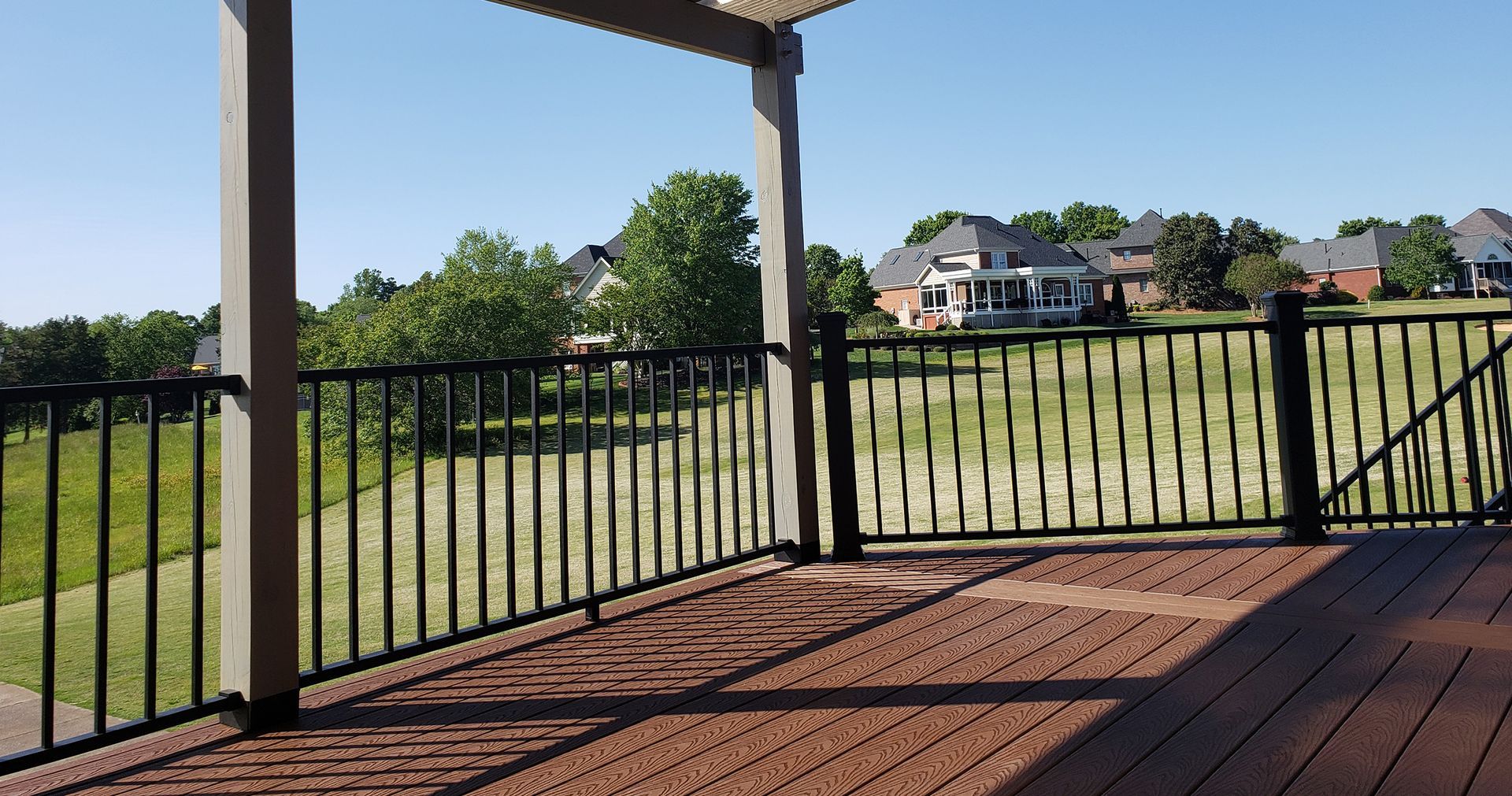 A wooden deck with a metal railing and a pergola.
