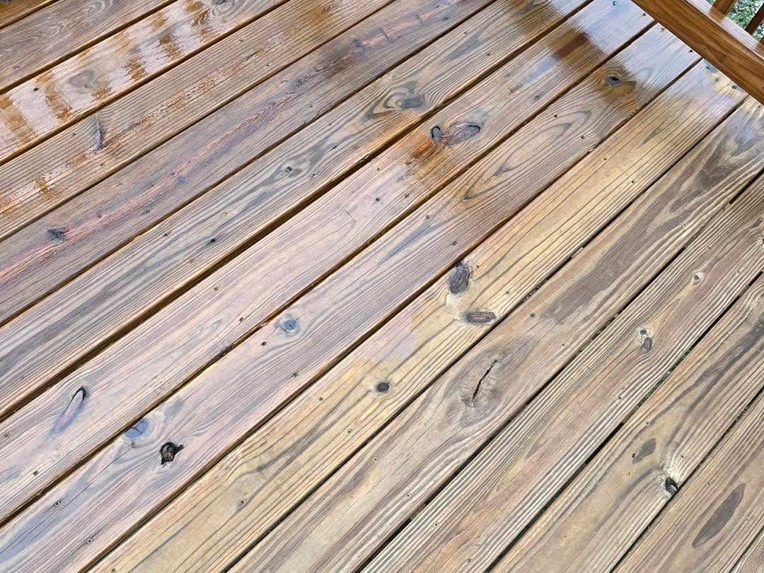 Weathered wooden deck boards with scattered dark knots and bolts, viewed at an angle