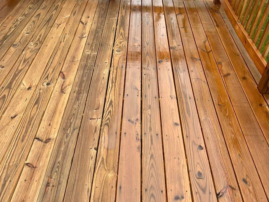 Wooden deck boards with a wet, weathered surface and a railing along the side