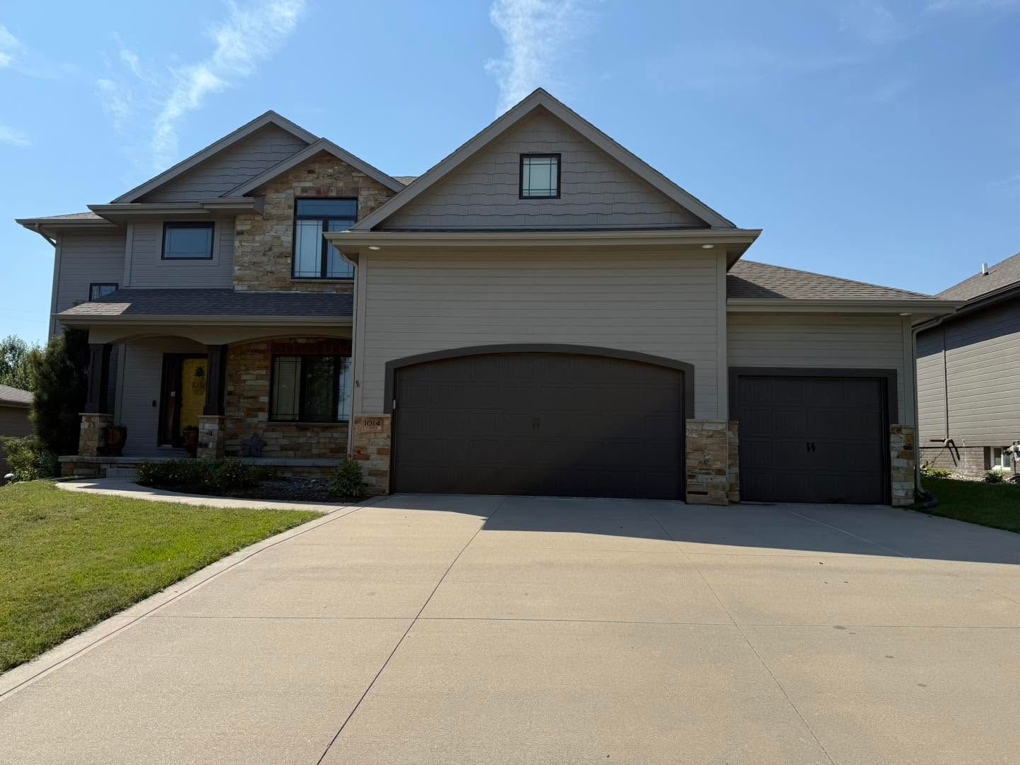 Suburban two-story house with a three-car garage and wide concrete driveway