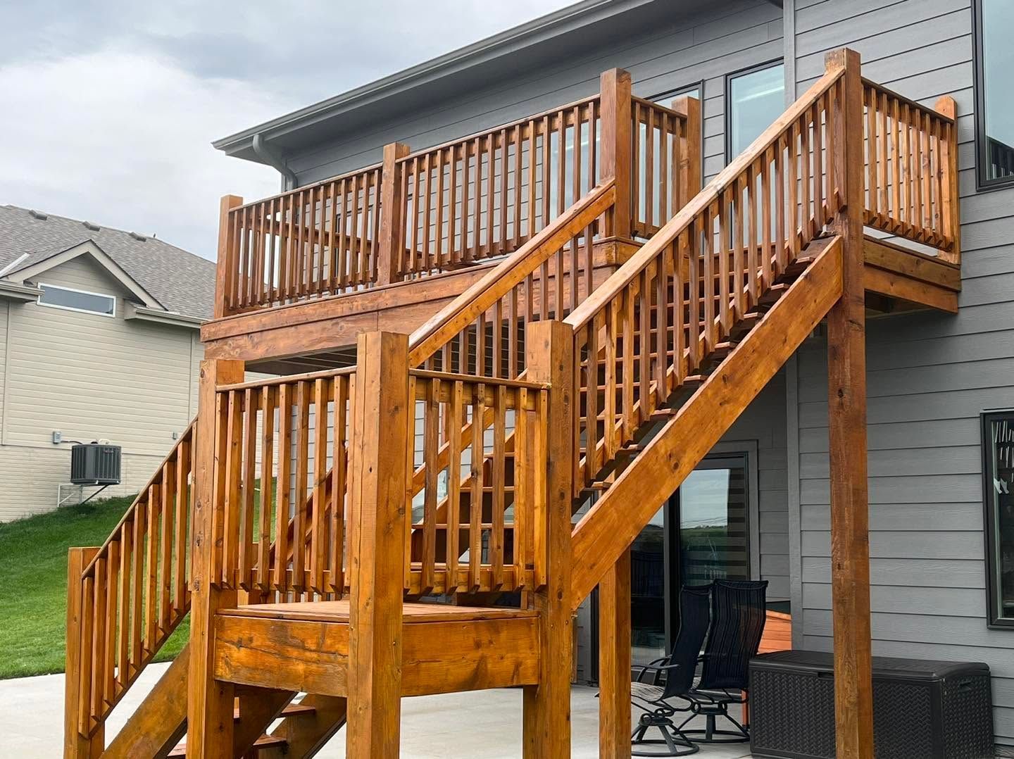 Wooden outdoor staircase and deck on the side of a gray house