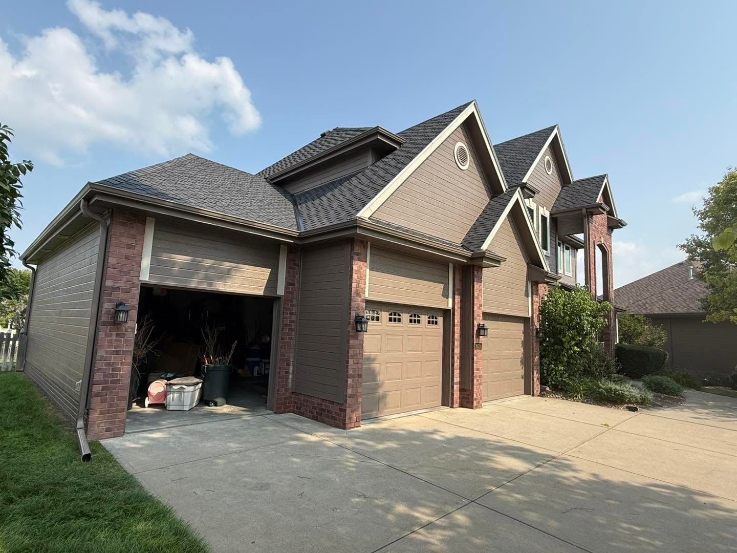 Suburban brick house with two-car garage and open garage door on a sunny day