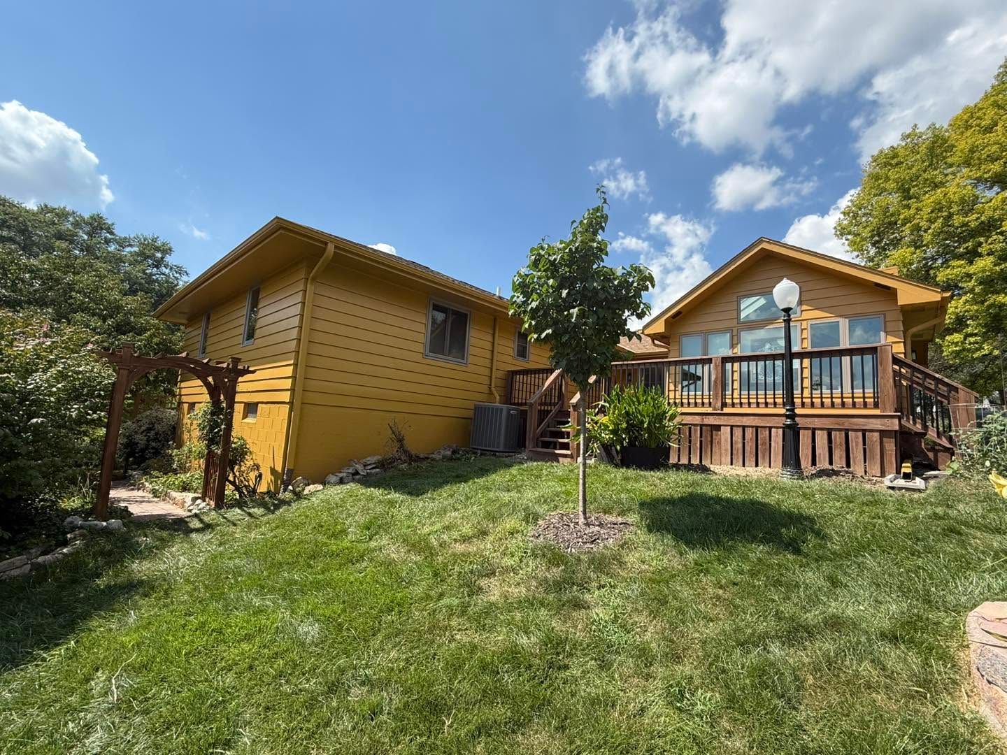 Yellow wooden cabins on a grassy hillside under a blue sky with trees and a porch railing