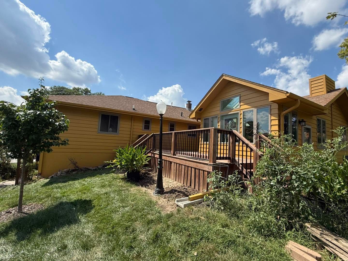 Rustic wooden house with a small porch and steps, surrounded by grass under a sunny blue sky