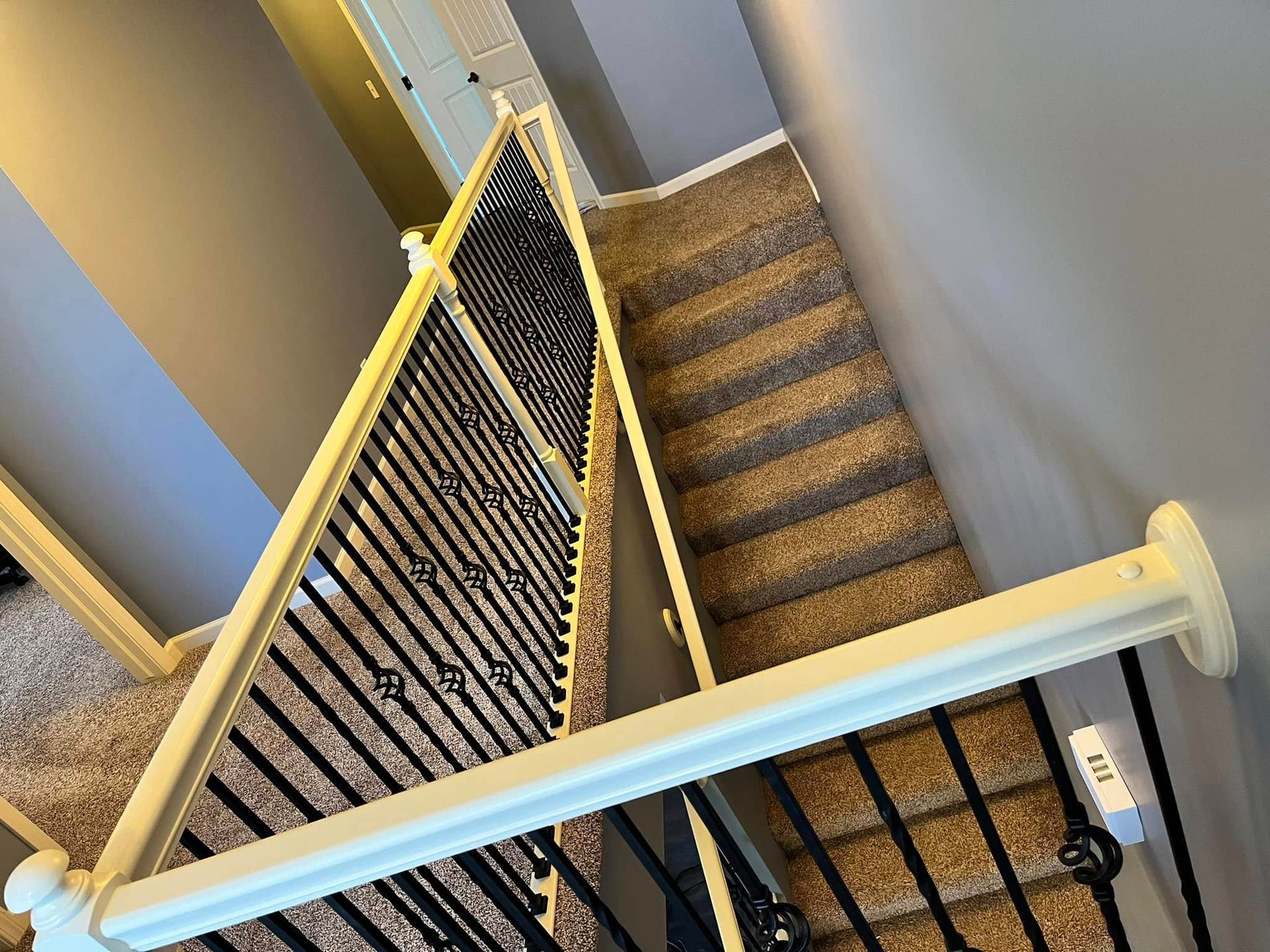 Stairwell with carpeted steps and a white child safety gate blocking the top landing