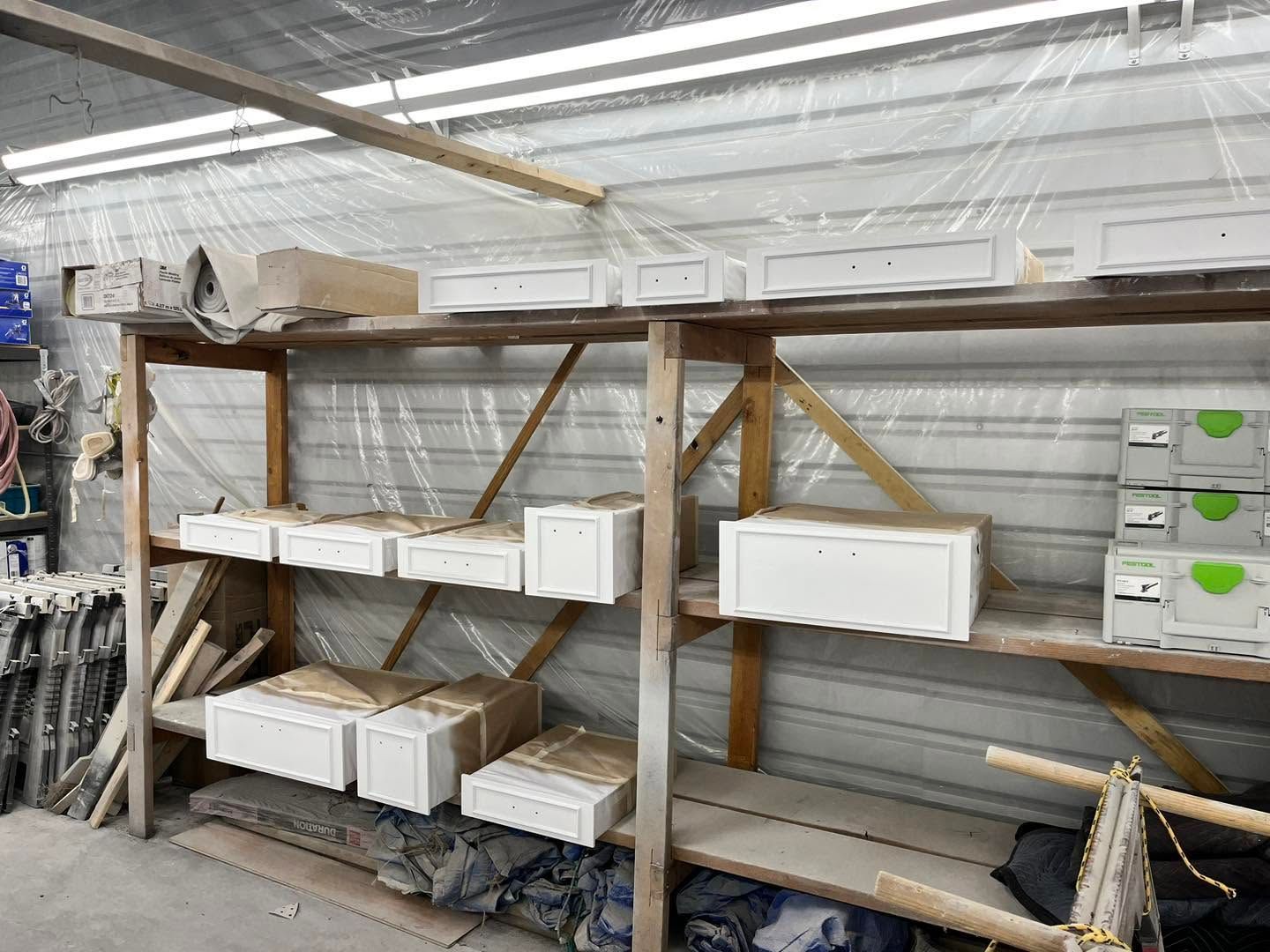 Workshop shelves holding white boxes and long wooden boards in a storage area