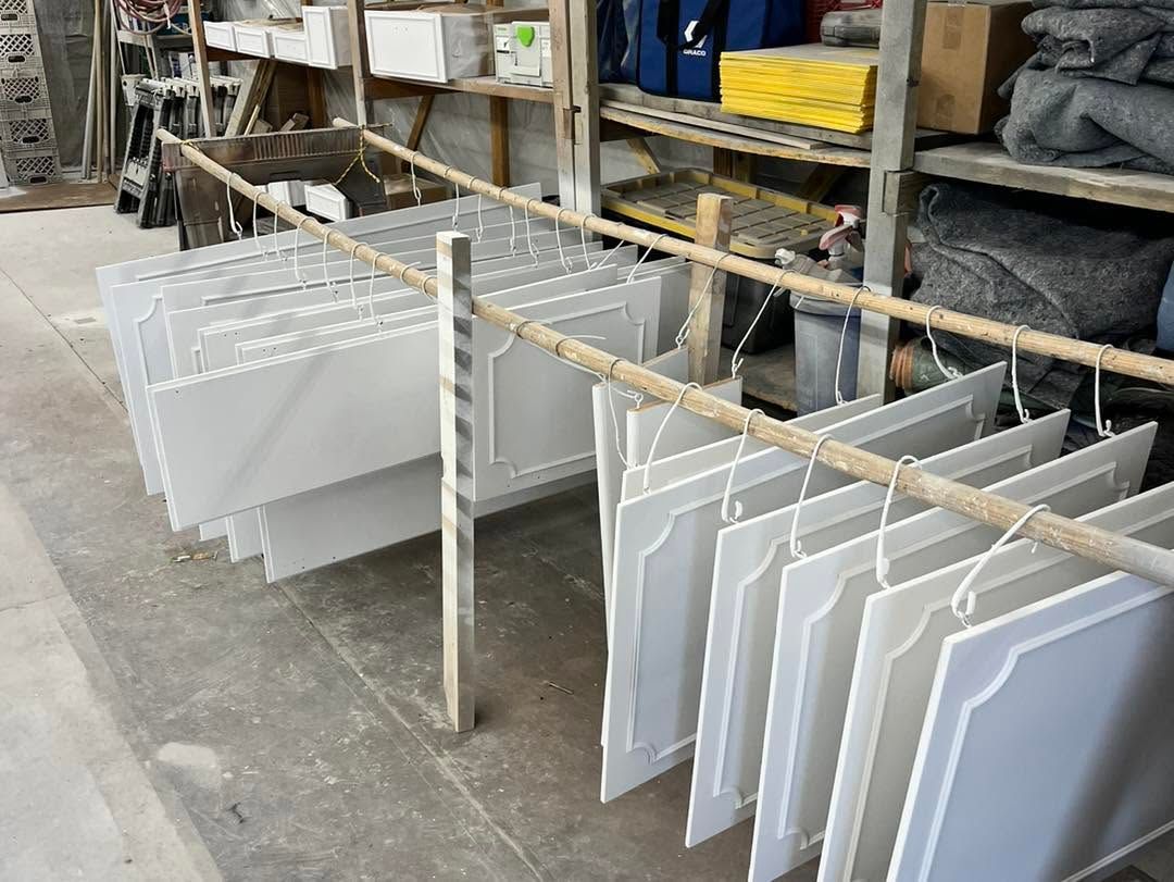 White panels hanging on a drying rack in a workshop, with shelves and tools in the background