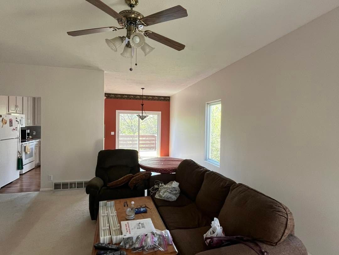 Living room with brown sectional, ceiling fan, and bright window by a red front door