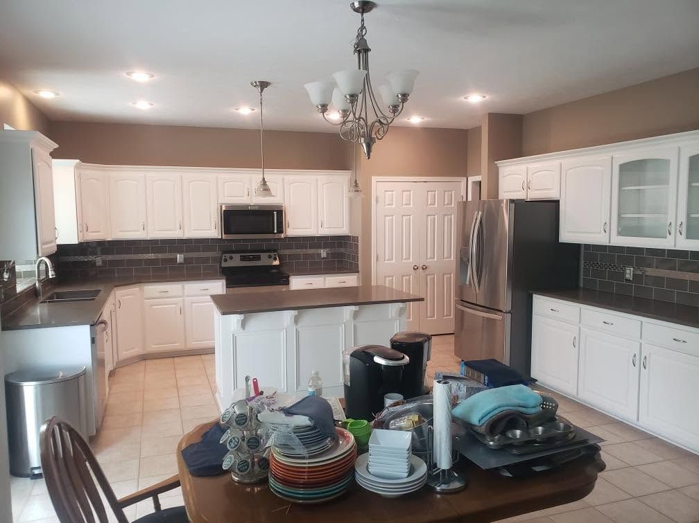Bright kitchen with white cabinets, stainless steel appliances, island, and chandelier.