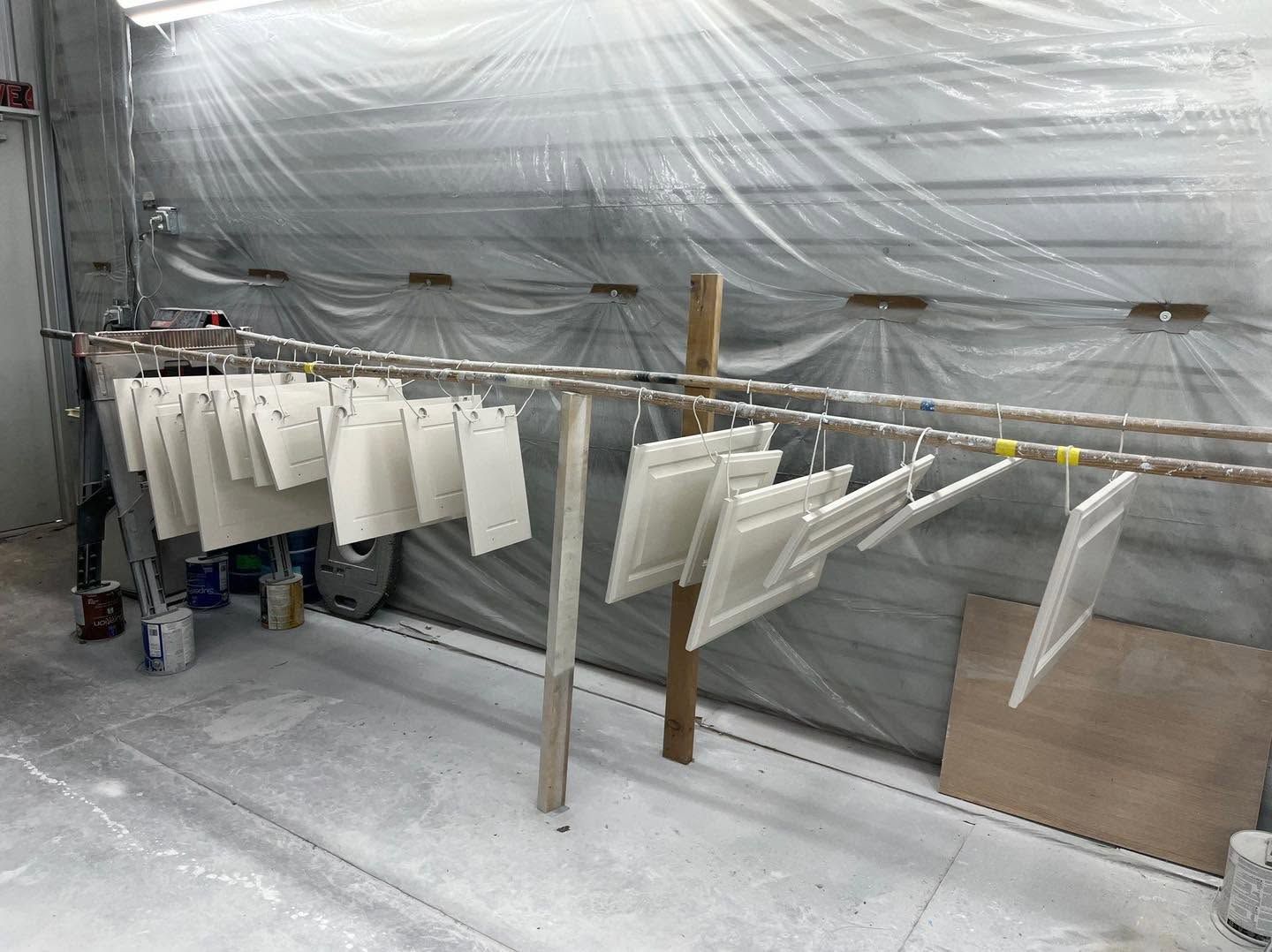 White panels drying on a line in a plastic-covered workshop room