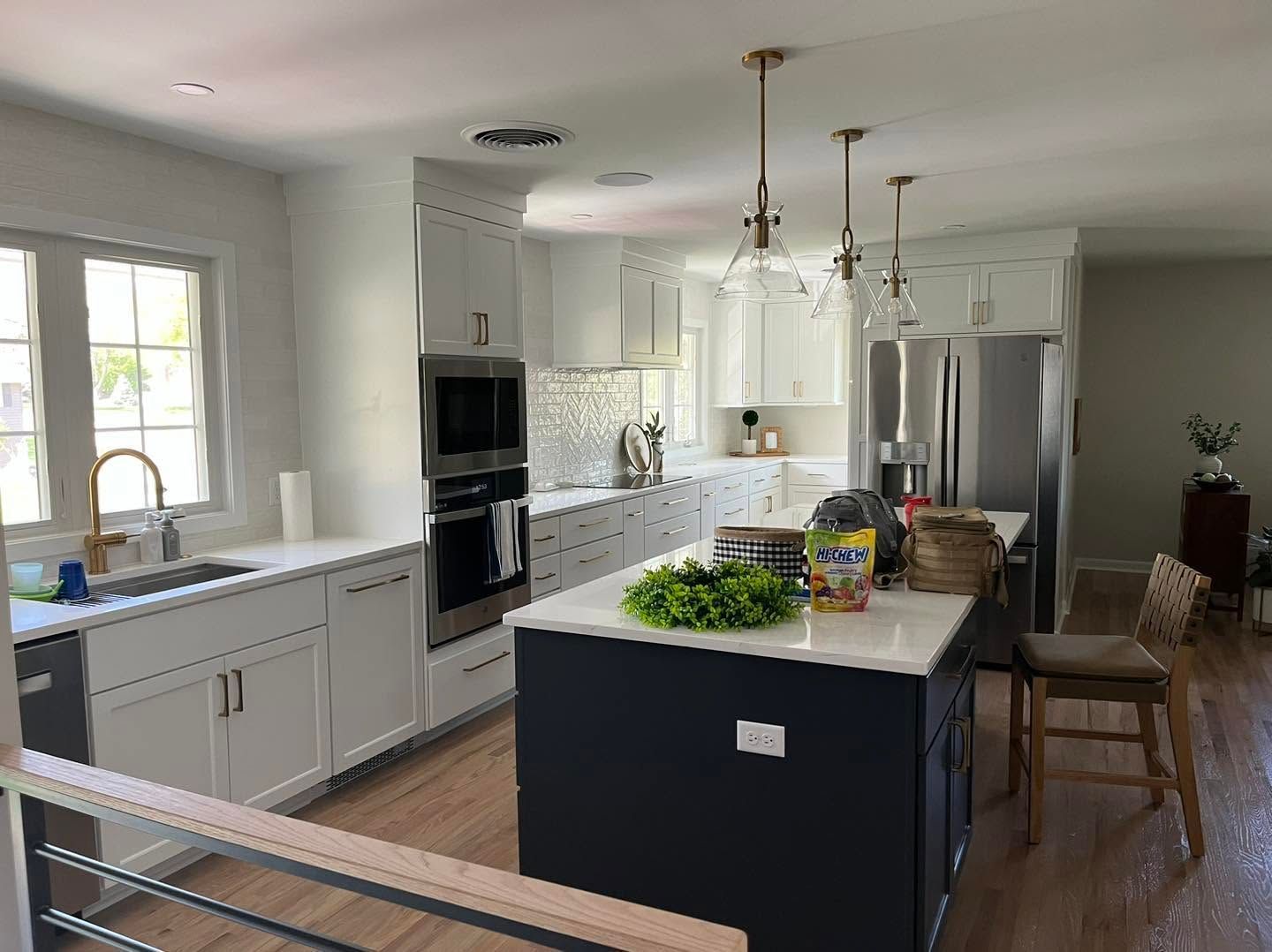 Bright modern kitchen with white cabinets, black island, stainless appliances, and hardwood floors