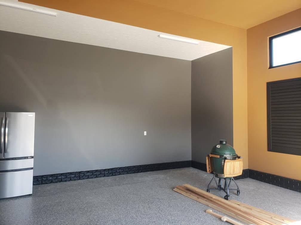 Empty room with gray walls, speckled floor, a refrigerator, and construction materials near a window