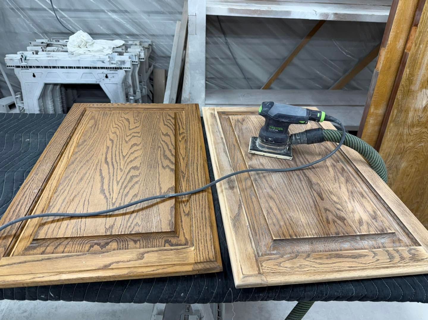Two wooden cabinet doors with a power sander on one door in a workshop