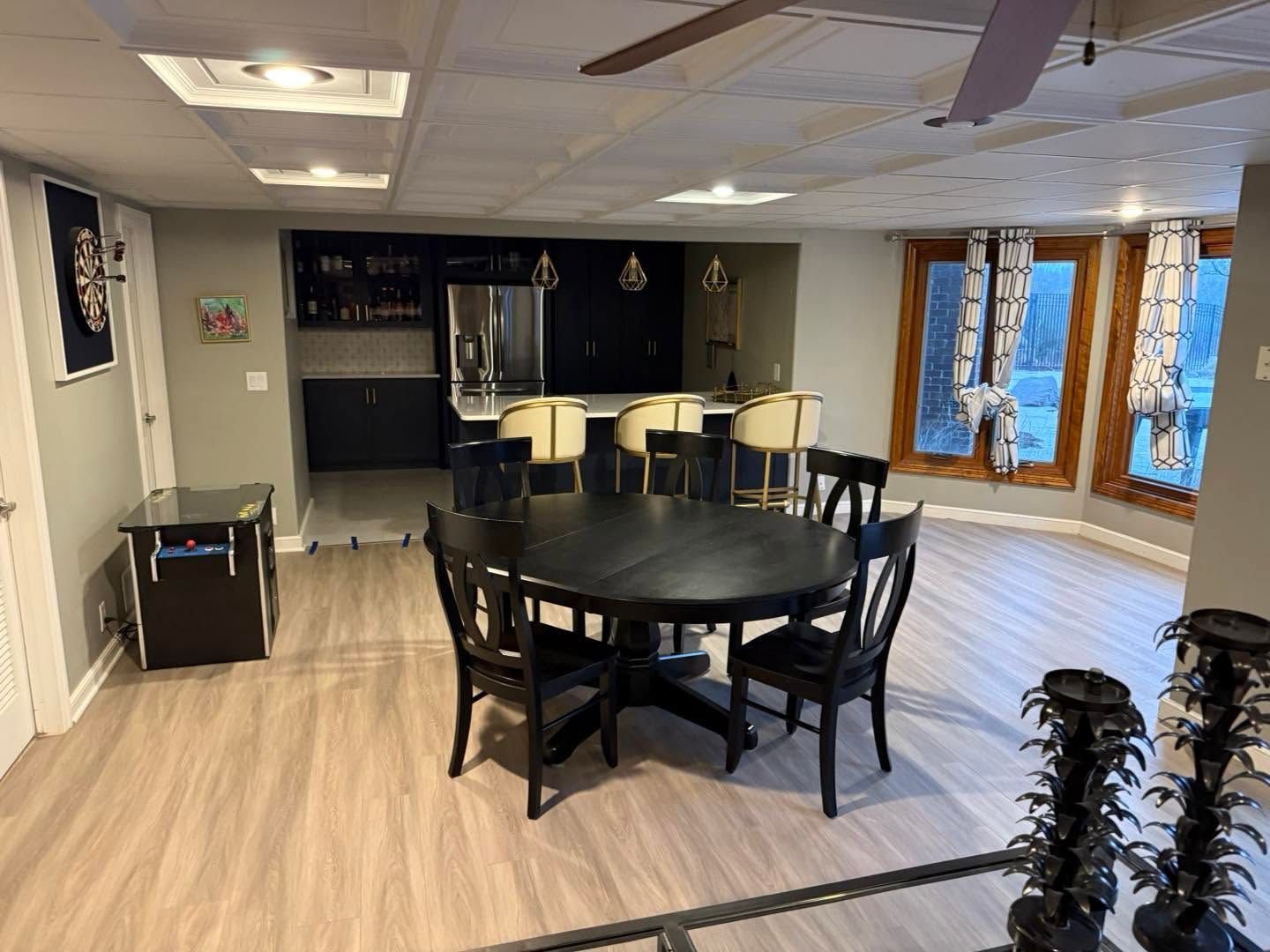 Spacious dining room with a black table, matching chairs, and a kitchen area in the background.