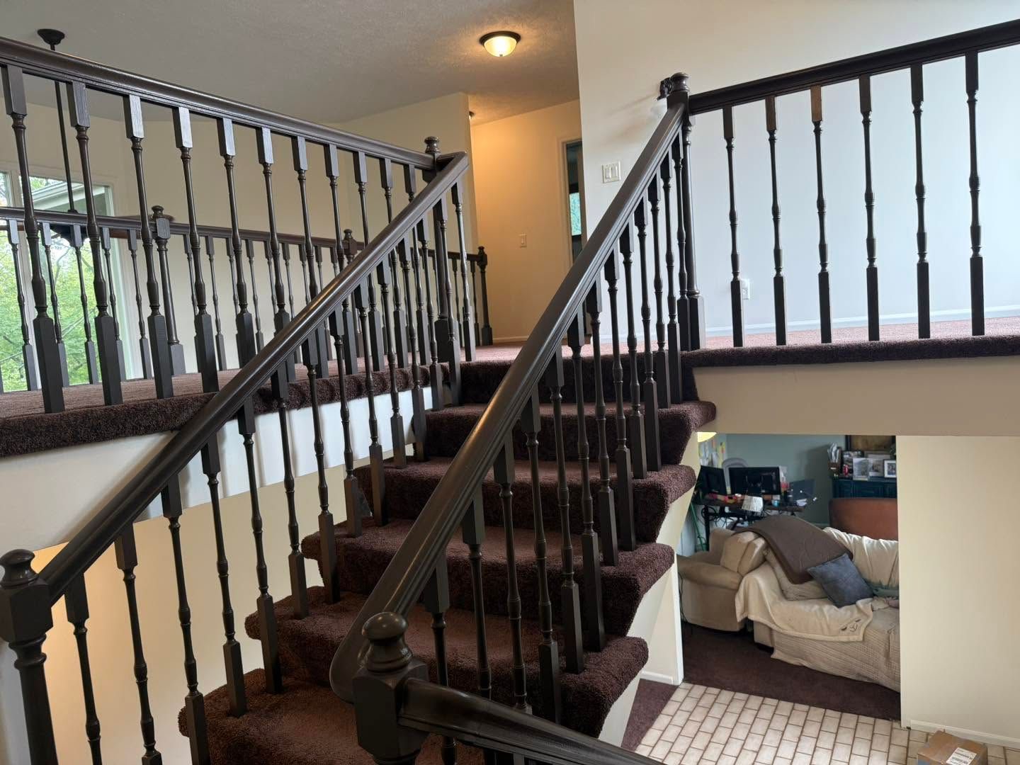 Interior staircase with dark railings and carpeted steps in a bright home hallway.