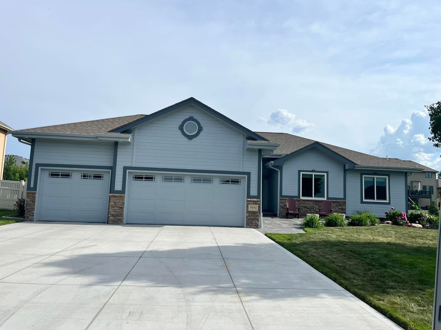 Single-story suburban house with three-car garage and a wide concrete driveway