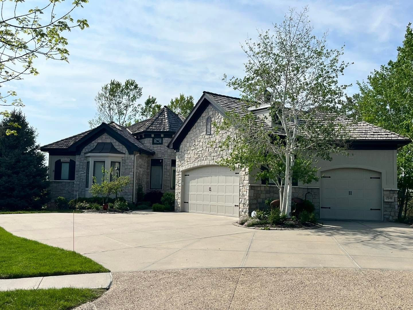 Suburban house with three-car garage, stone facade, and trees in the front yard