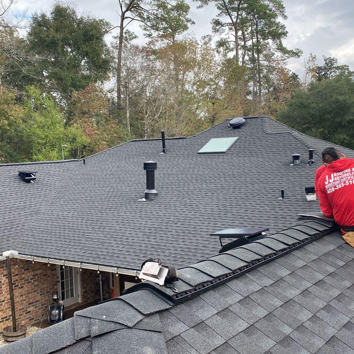 a man in a red shirt is working on the roof of a house .