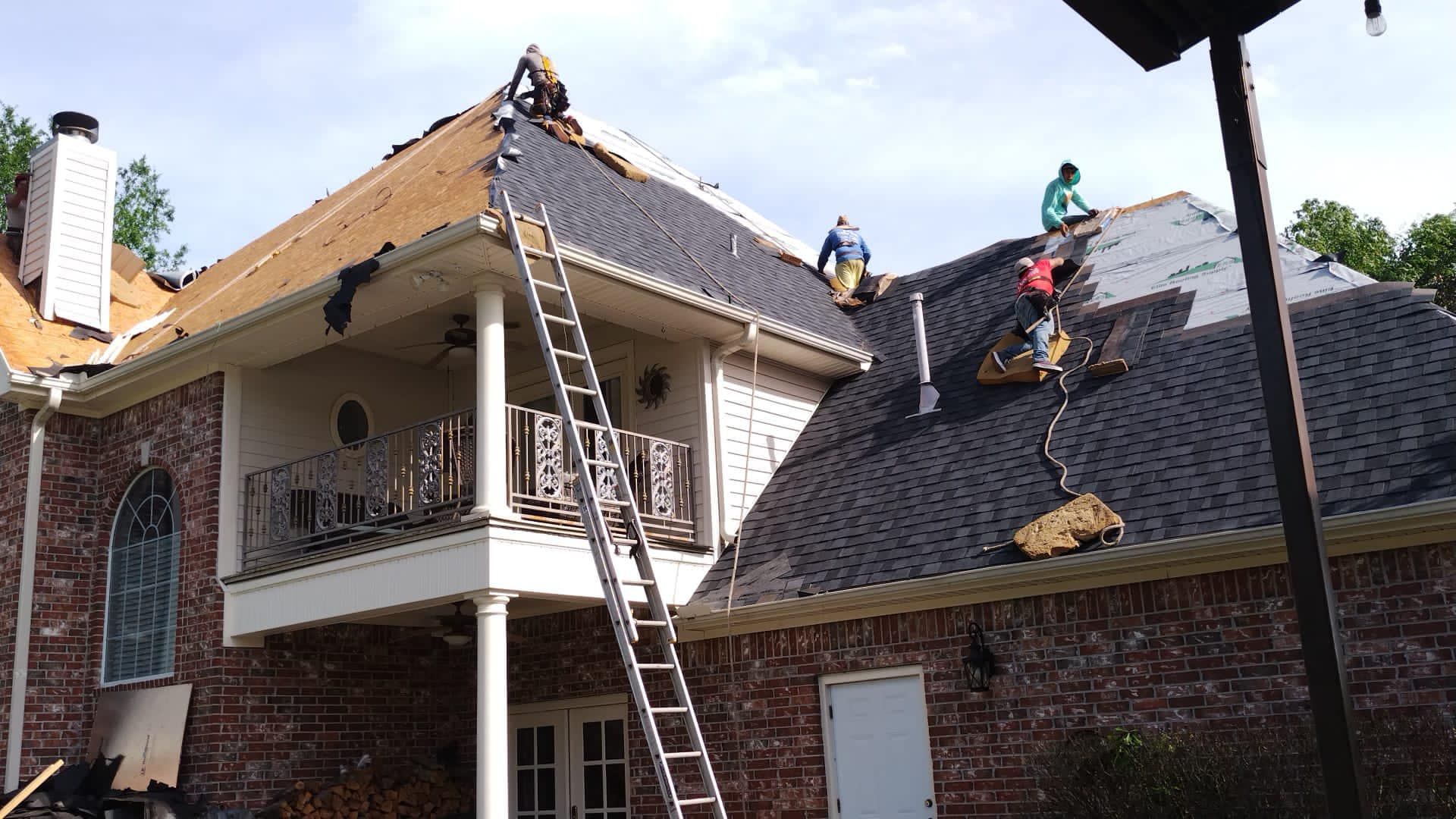 a group of people are working on the roof of a house .