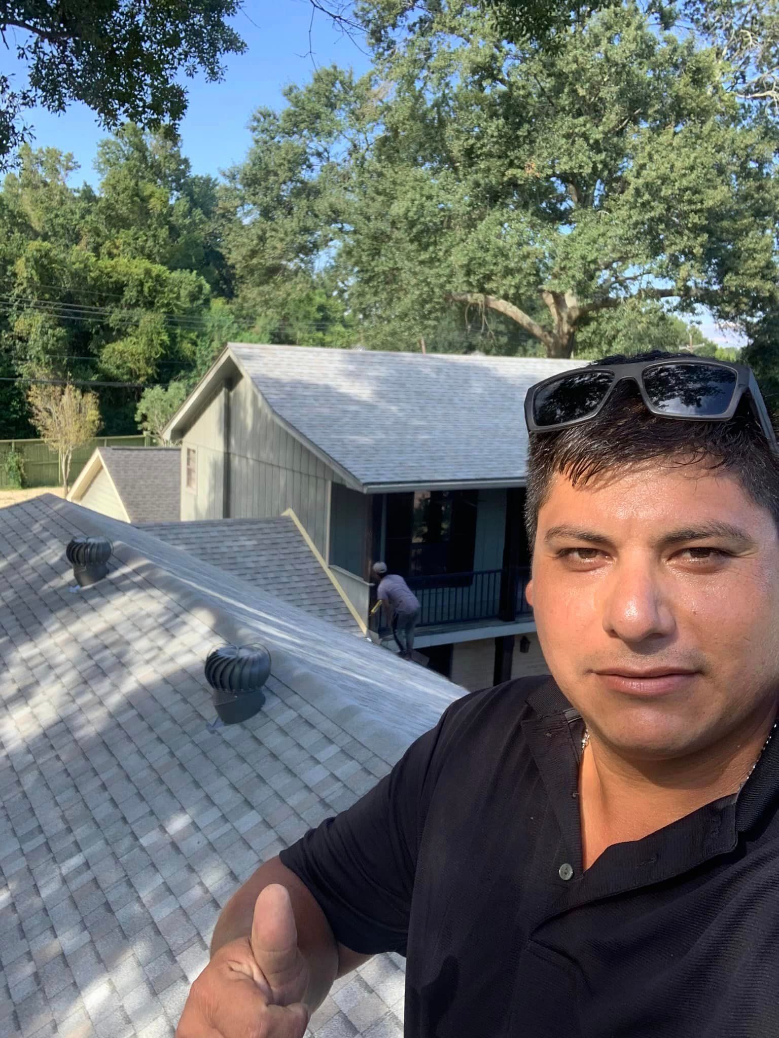 a man is standing on the roof of a house giving a thumbs up .