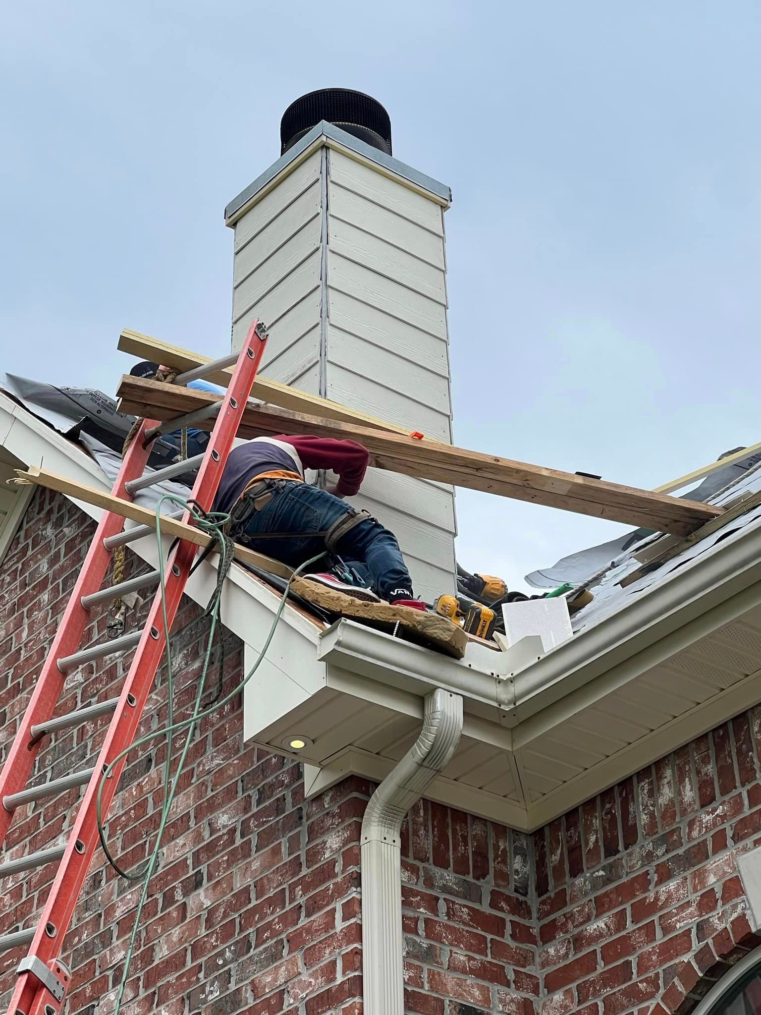 a man is laying on a ladder on the roof of a house .