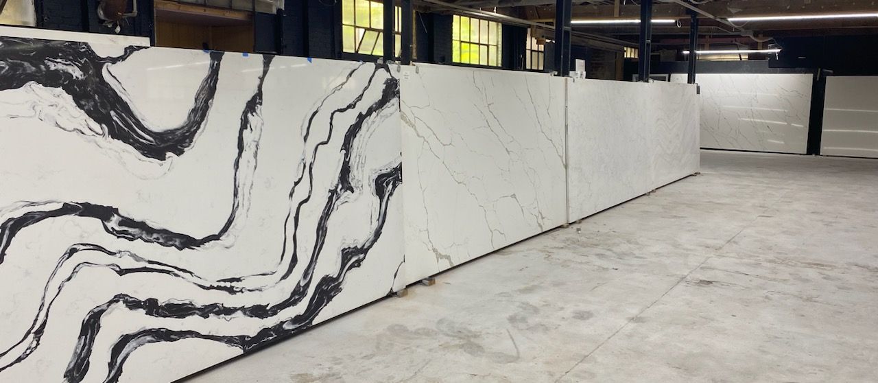 Large slabs of white stone with dark gray veining are arranged in a warehouse.