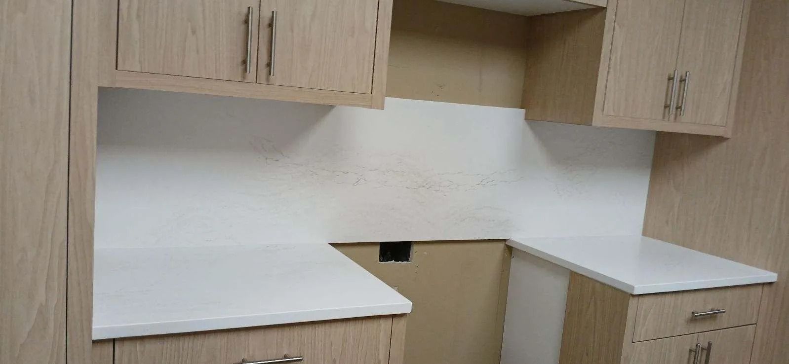 A kitchen with wooden cabinets and white counter tops.