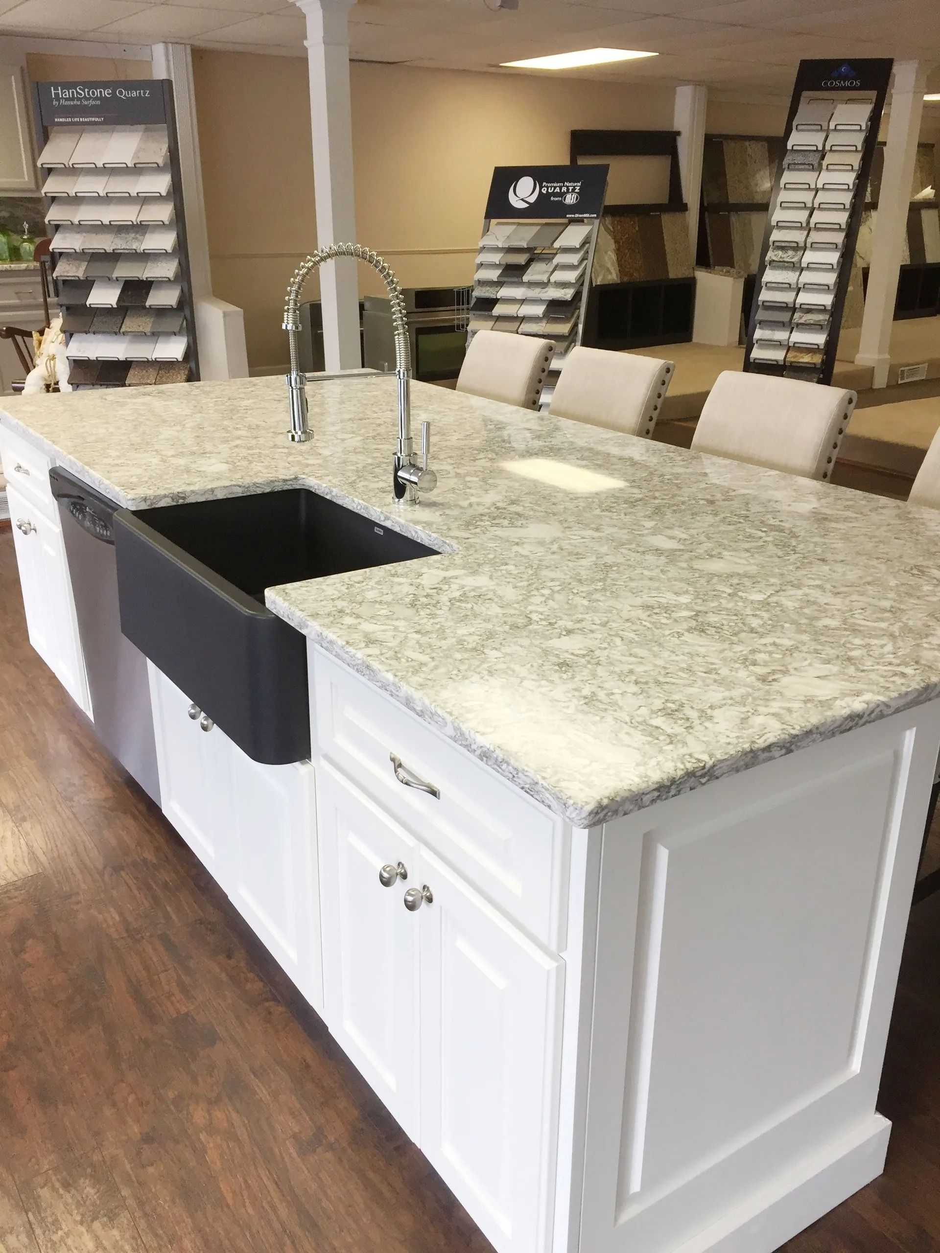 A kitchen island with a black sink and white cabinets