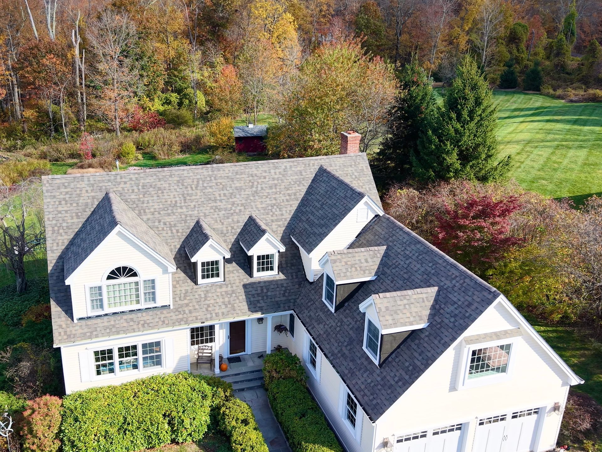 White house with gray roof and autumn foliage.