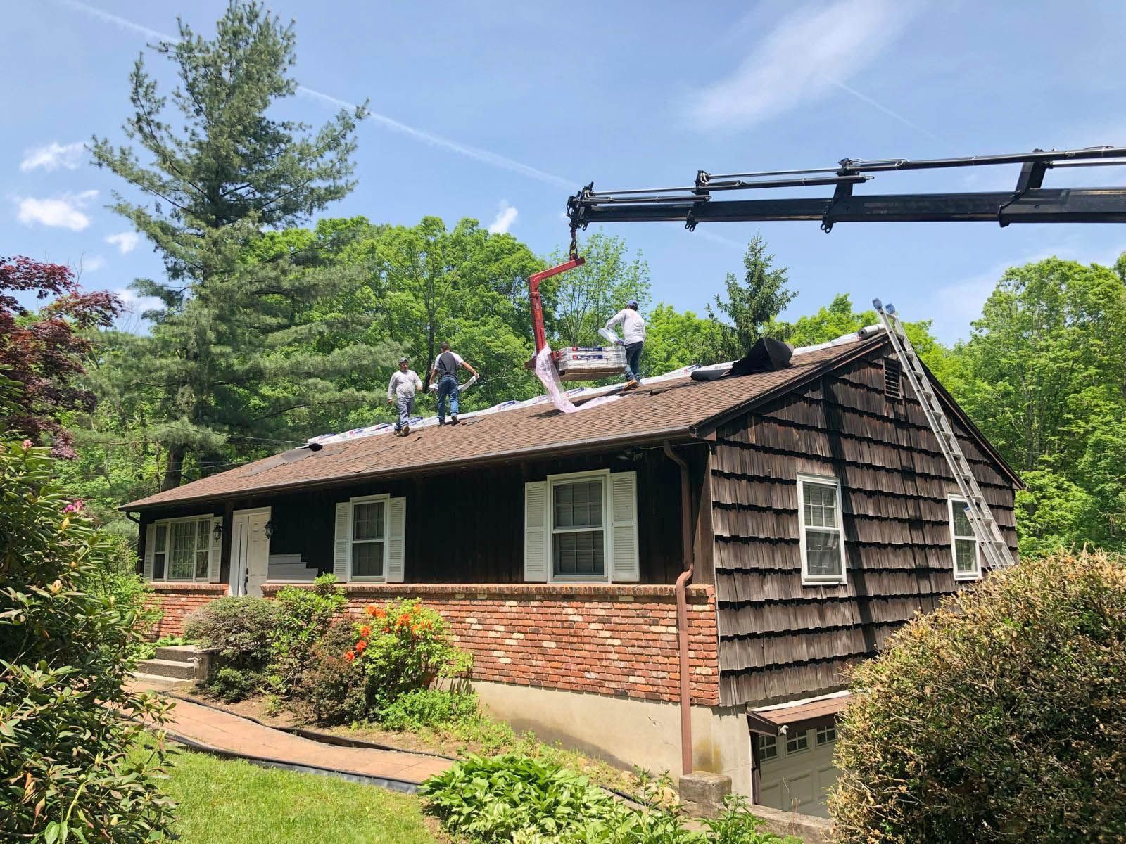 A group of people are working on the roof of a house