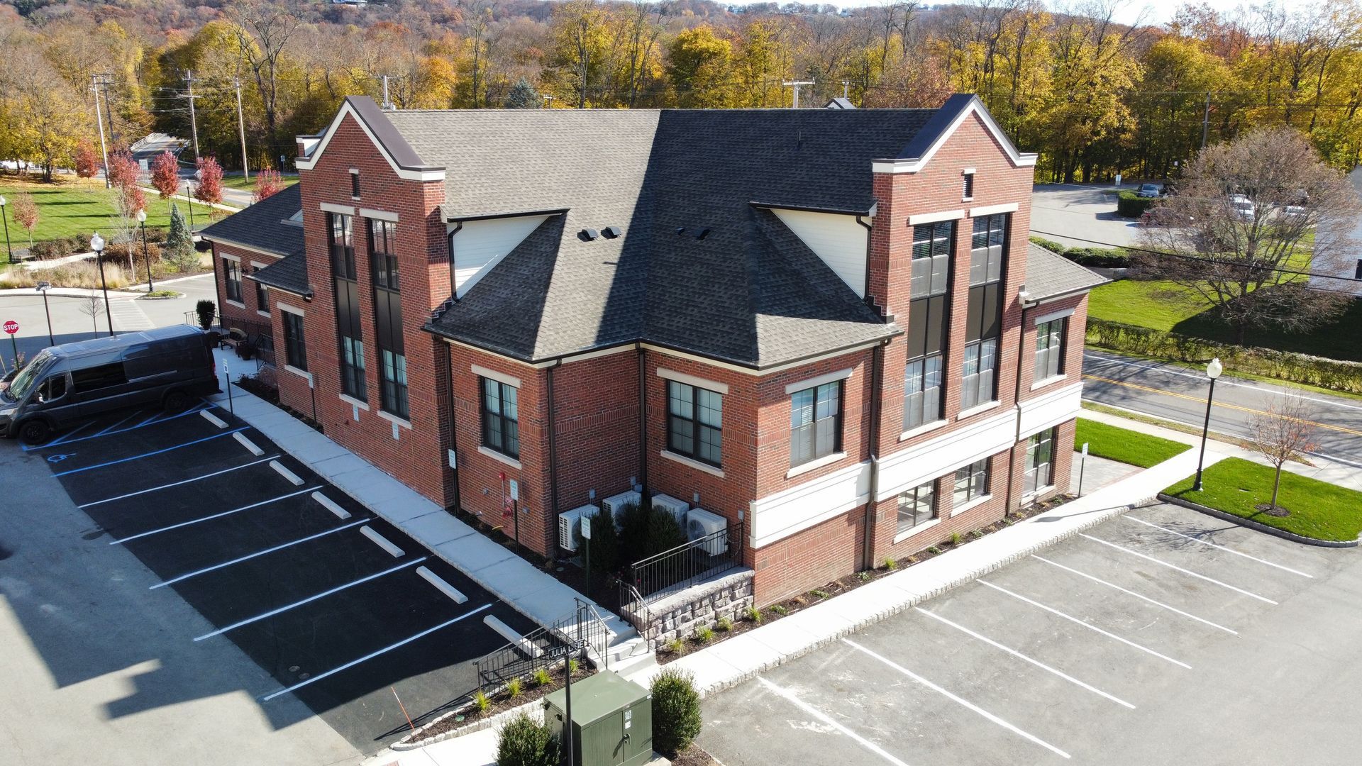 An aerial view of a large brick building with a parking lot in front of it.