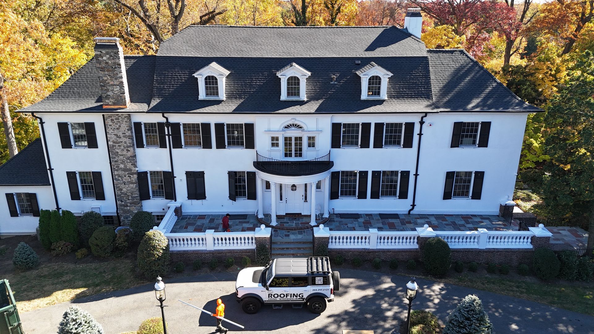 An aerial view of a large white house with a black roof