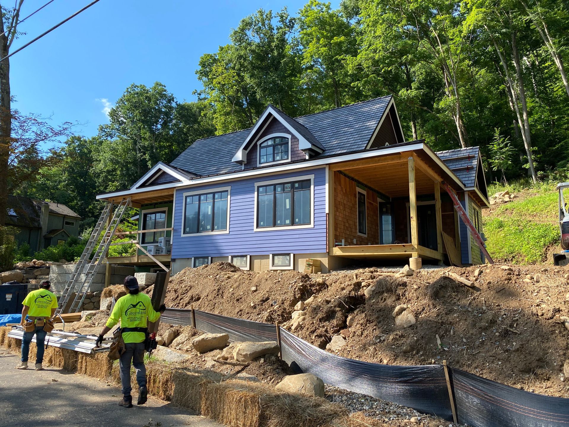 A purple house is being built on a hill in the woods.