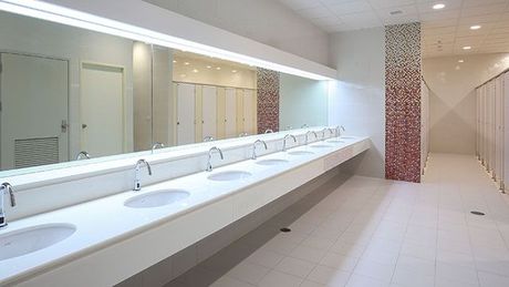 A public restroom with a long row of sinks and mirrors.