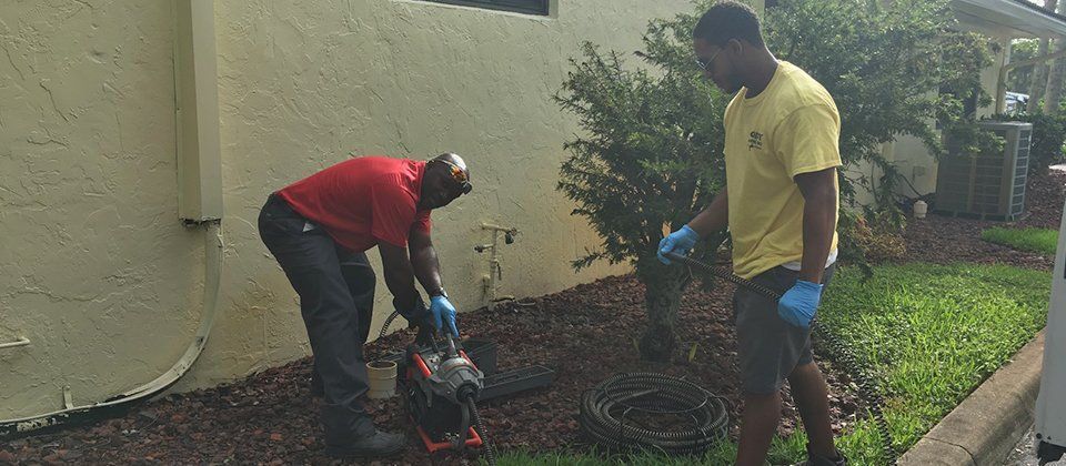 Two men are working on a drain in a yard.