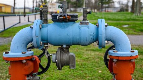 A close up of a blue and orange water pipe in a park.