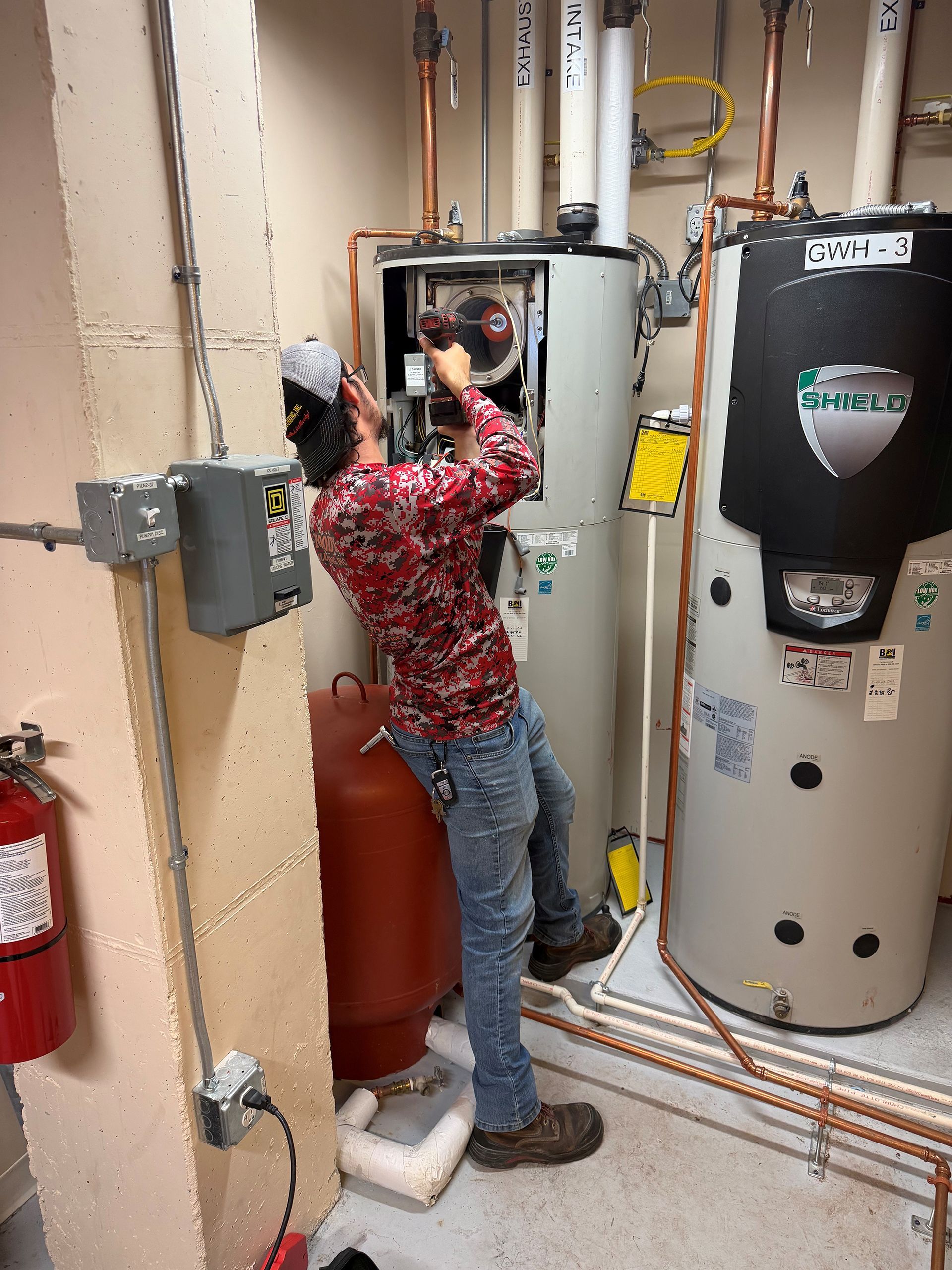 Plumber working on equipment in a utility room