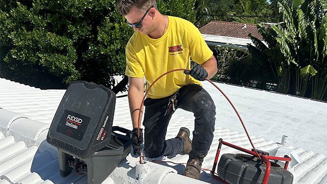 A plumber is fixing a sink in a kitchen with a wrench.