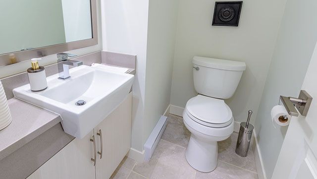 A bathroom with a toilet , sink and mirror.