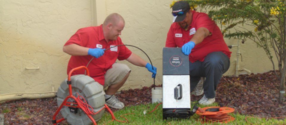 Two men are working on a drain in a yard.