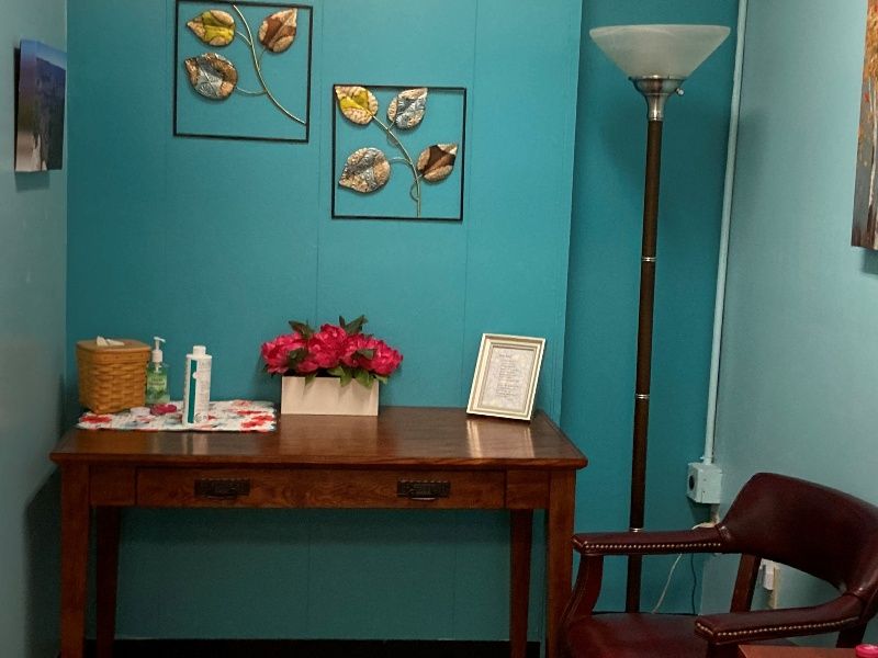 A desk with a vase of flowers on it in a room with blue walls