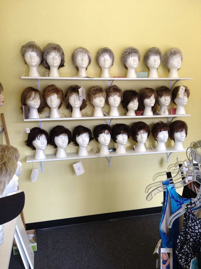 A row of mannequin heads with wigs on shelves in a store
