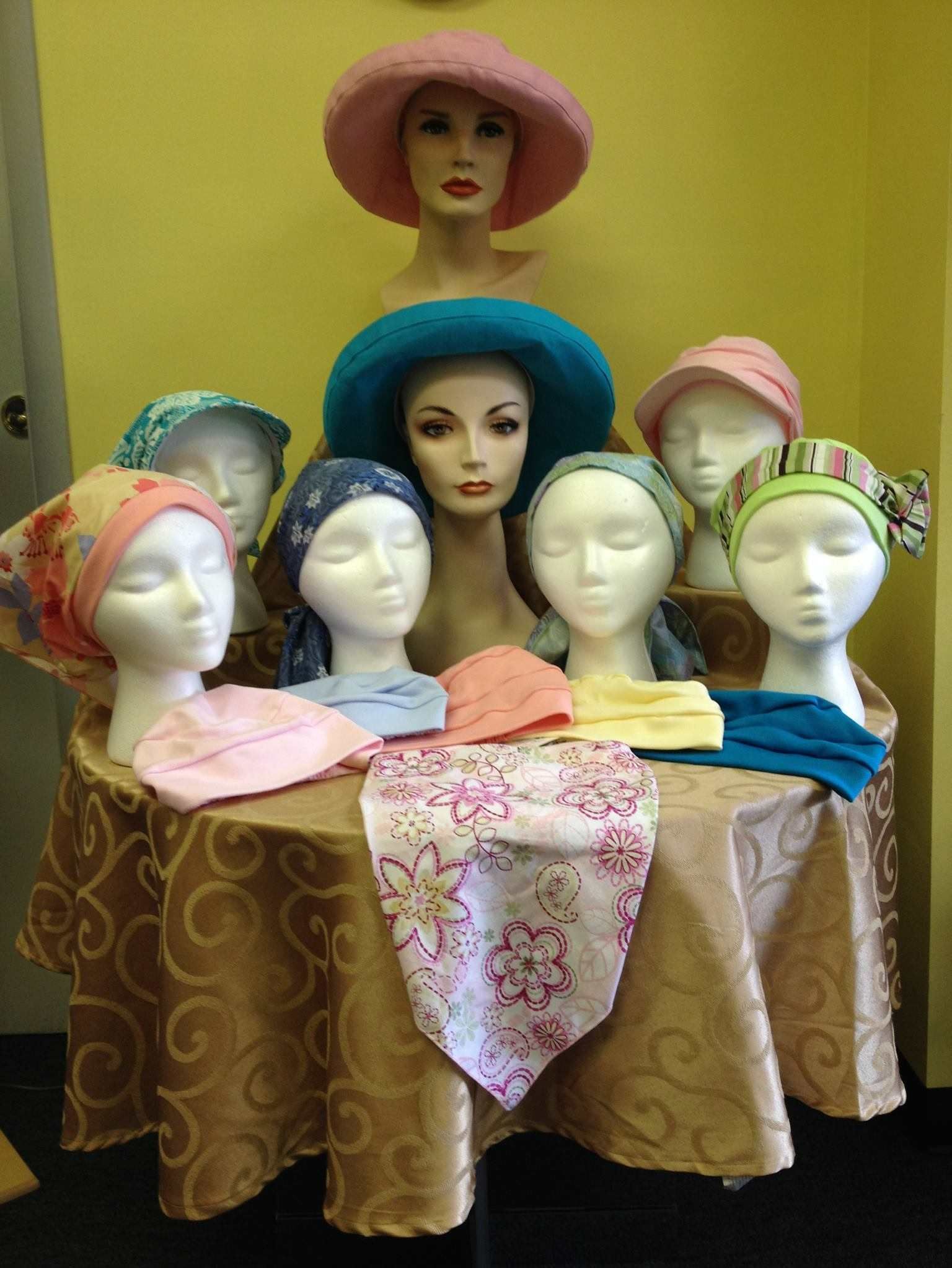 A table with a bunch of mannequins wearing hats and scarves