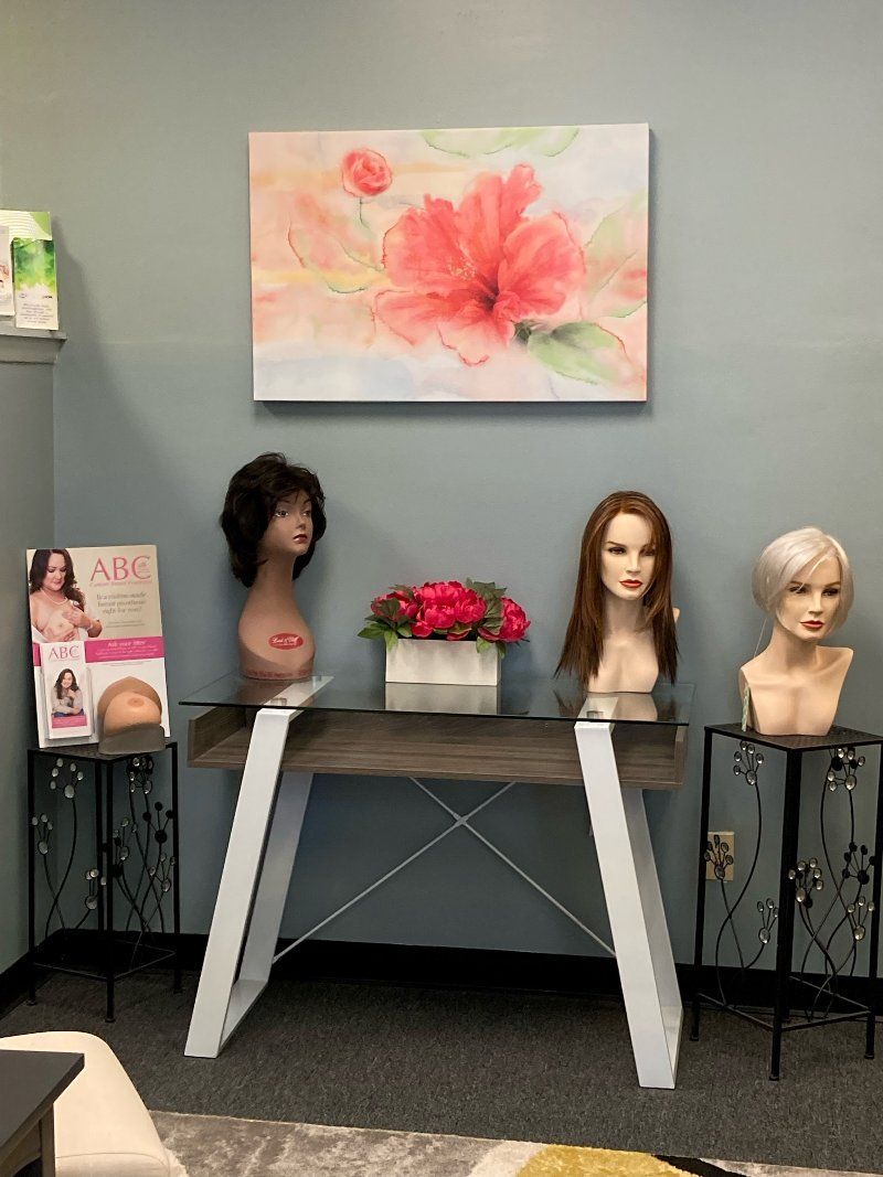 A table with wigs on it and a painting on the wall above it.