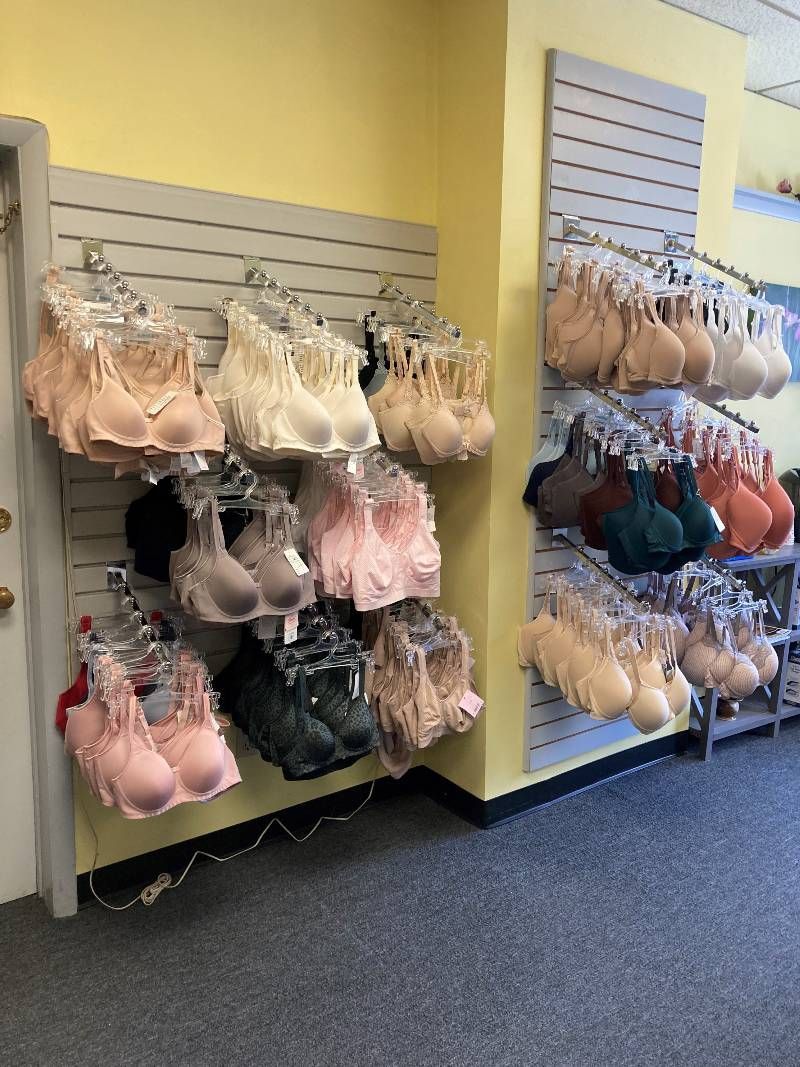 A bunch of bras are hanging on a wall in a store.